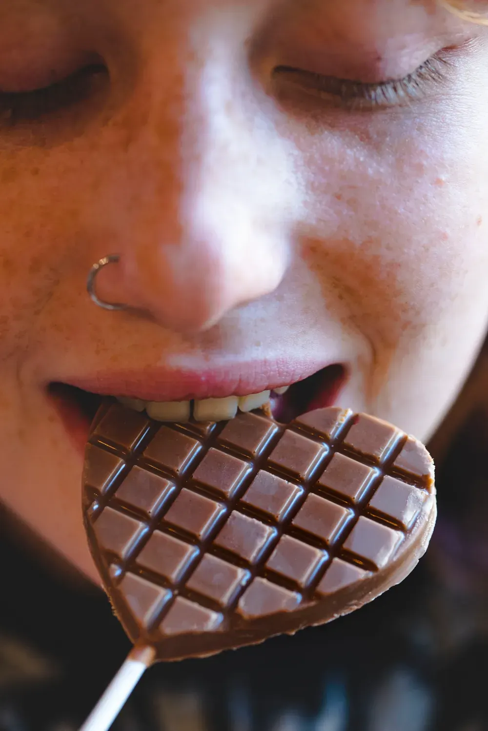 Tânără care mușcă dintr-o acadea-inimă din ciocolată cu caramel Choco Toni