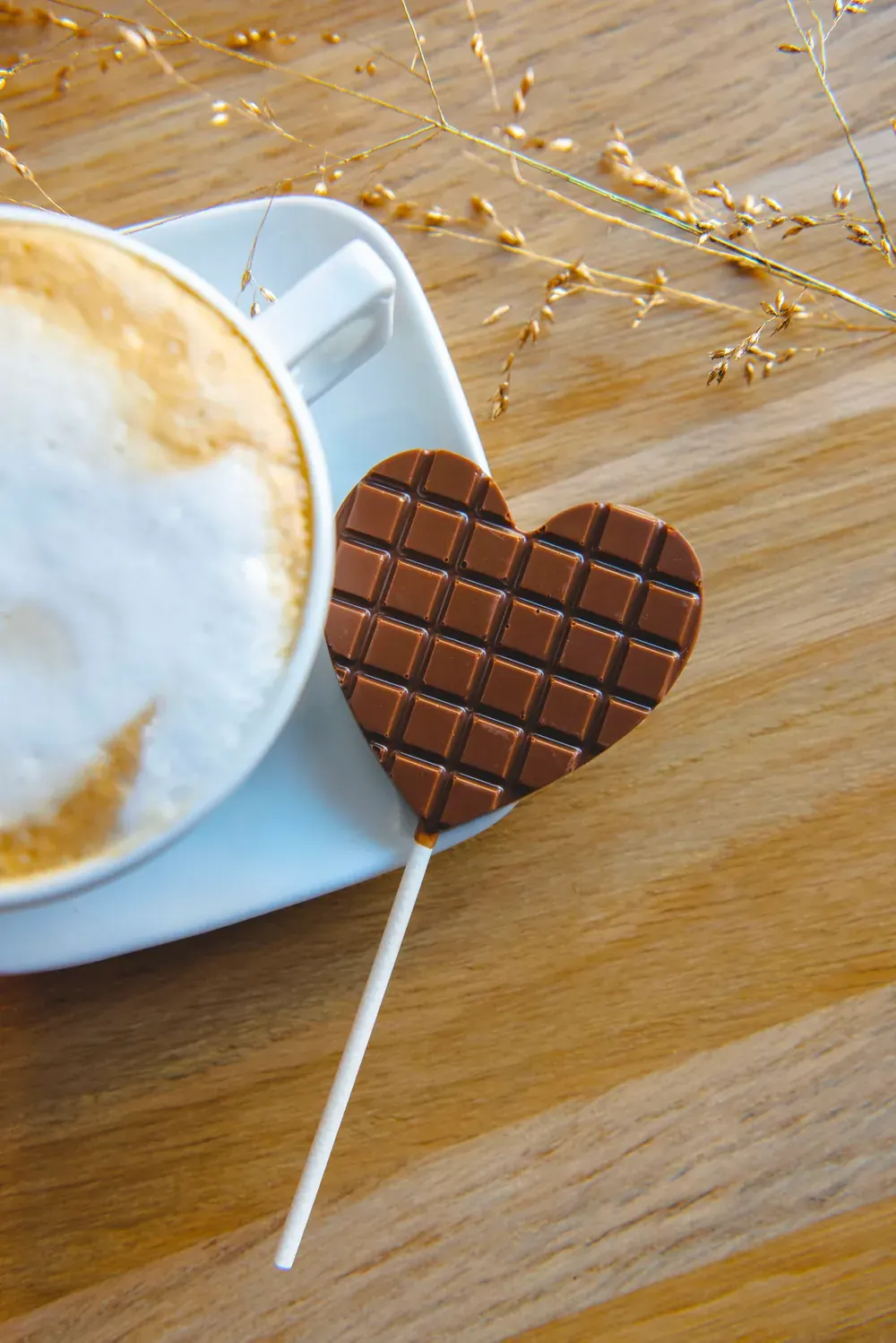 Acadea de ciocolată cu lapte Choco Toni în formă de inimă, lângă un cappuccino
