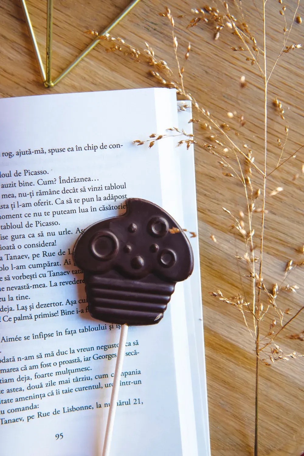 Acadea de ciocolată neagră Choco Toni în formă de brioșă, așezată pe o carte deschisă