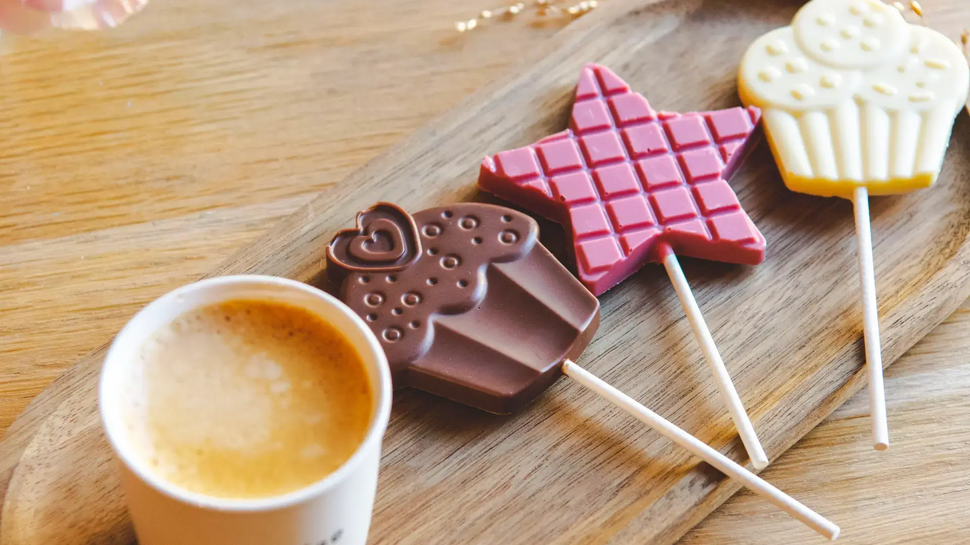 Acadele de ciocolată Choco Toni în formă de inimă, stea și brioșă, lângă o cafea