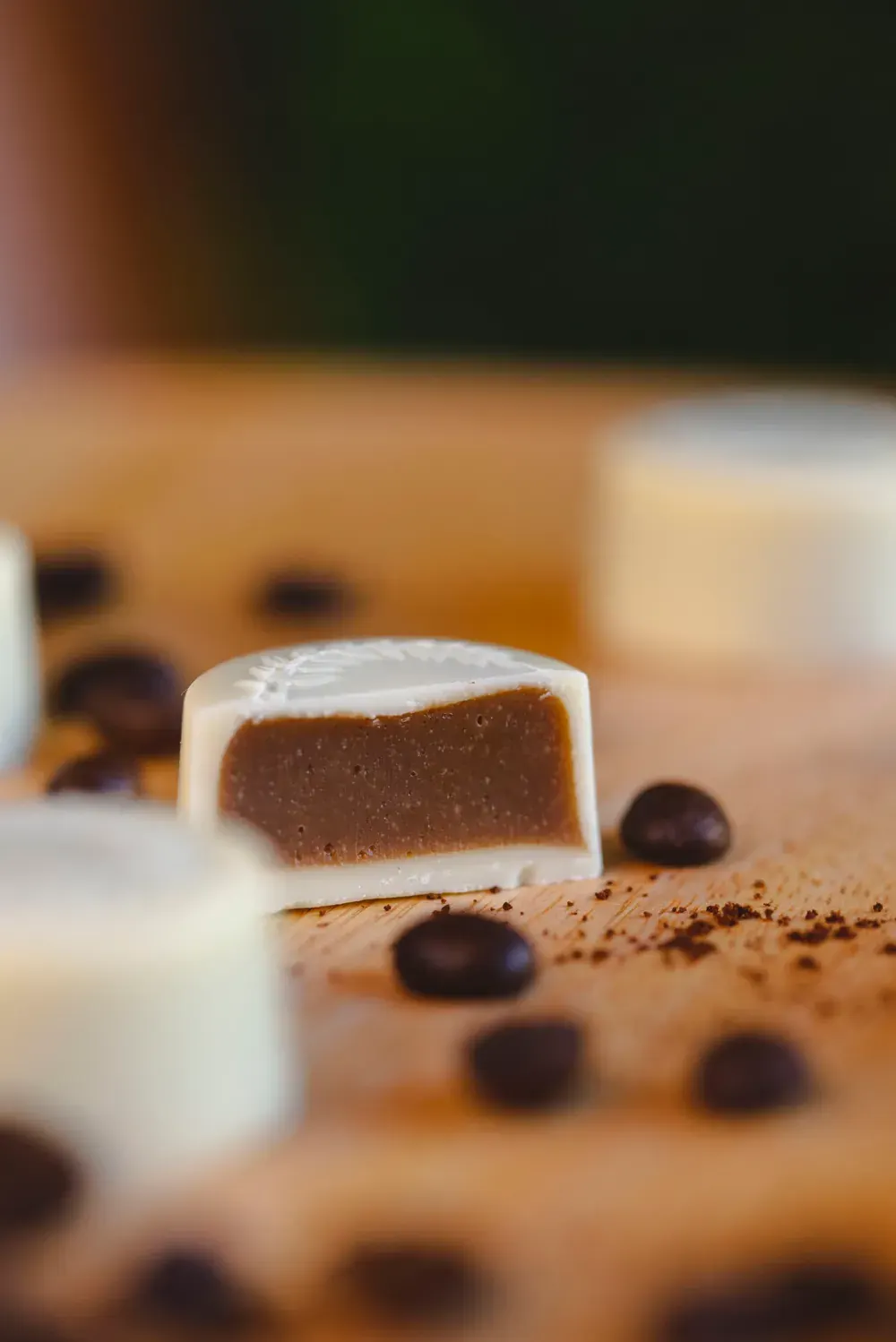 Bomboană de ciocolată albă cu cafea Choco Toni tăiată în două, printre boabe de cafea