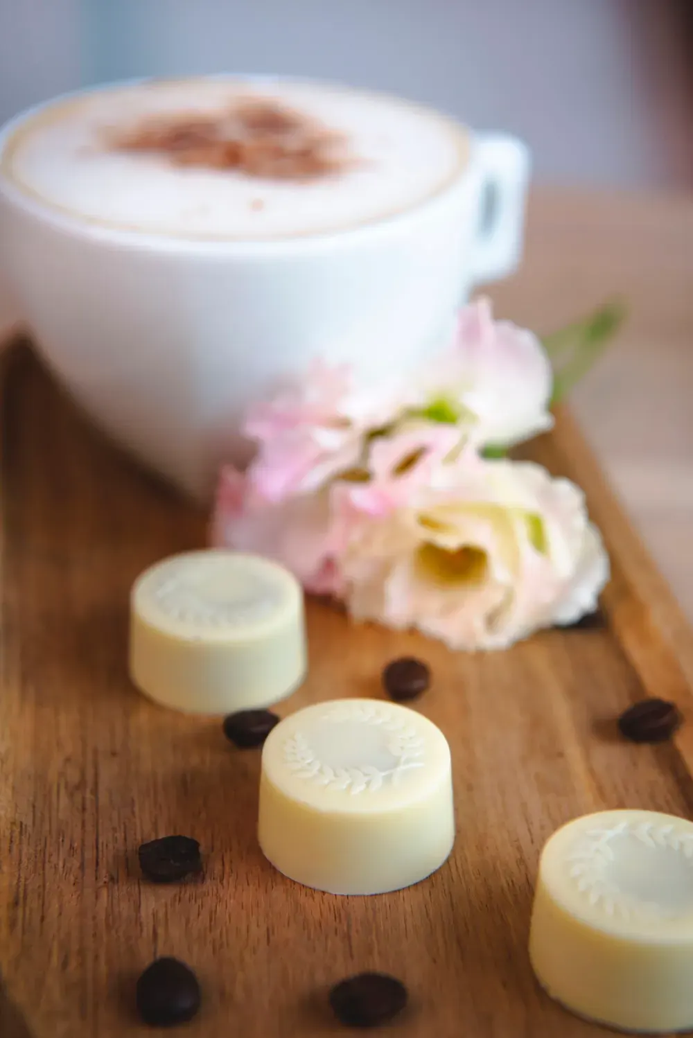 Bomboane de ciocolată albă cu cafea Choco Toni lângă un cappuccino și trandafiri