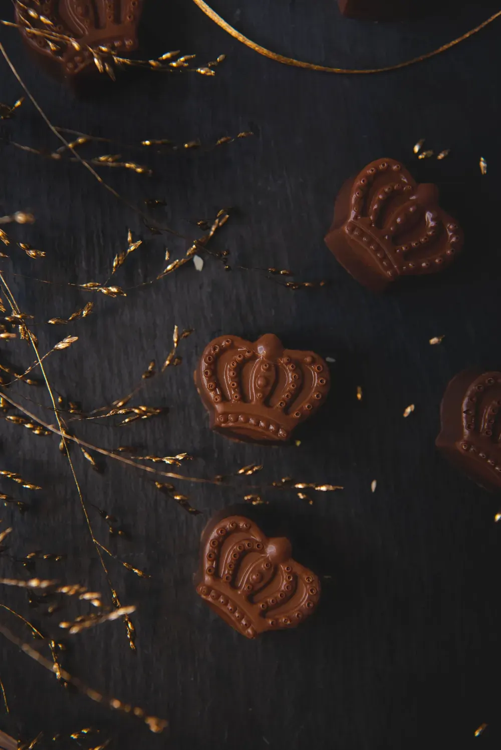 Bomboane de ciocolată cu lapte și cremă de whiskey Choco Toni în formă de coroană, pe fundal închis