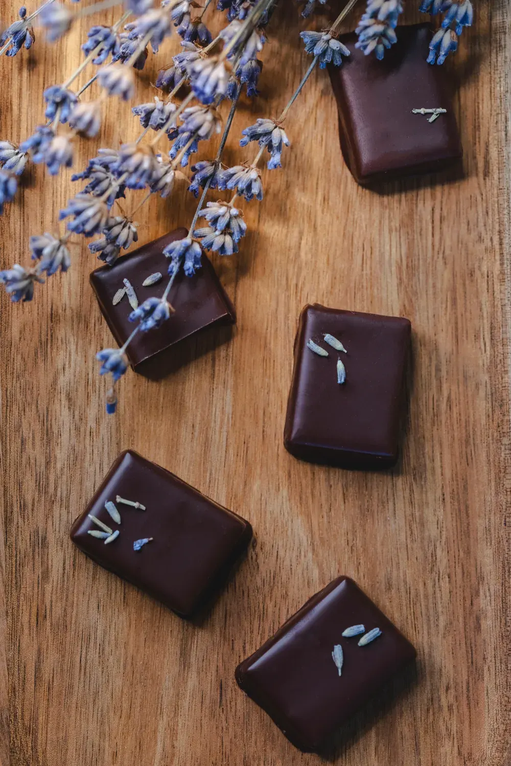 Bomboane de ciocolată neagră cu lavandă Choco Toni, cu flori de lavandă, pe lemn