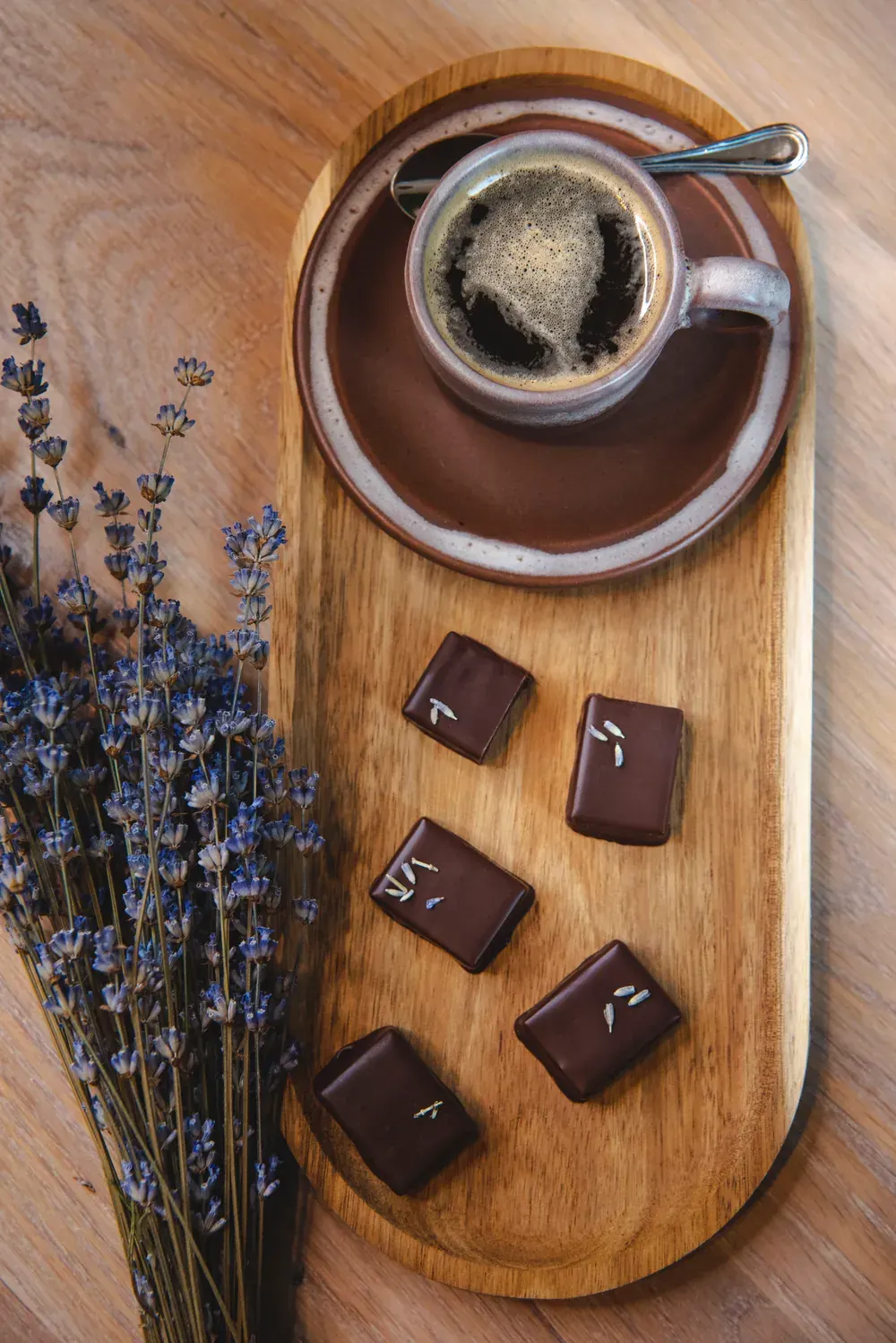 Bomboane de ciocolată neagră cu lavandă Choco Toni lângă o ceașcă de cafea și un buchet de lavandă