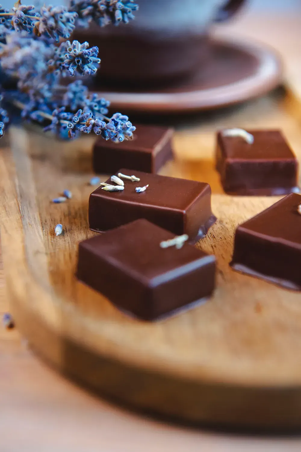 Bomboane pătrate de ciocolată neagră cu lavandă Choco Toni, pe un platou de lemn