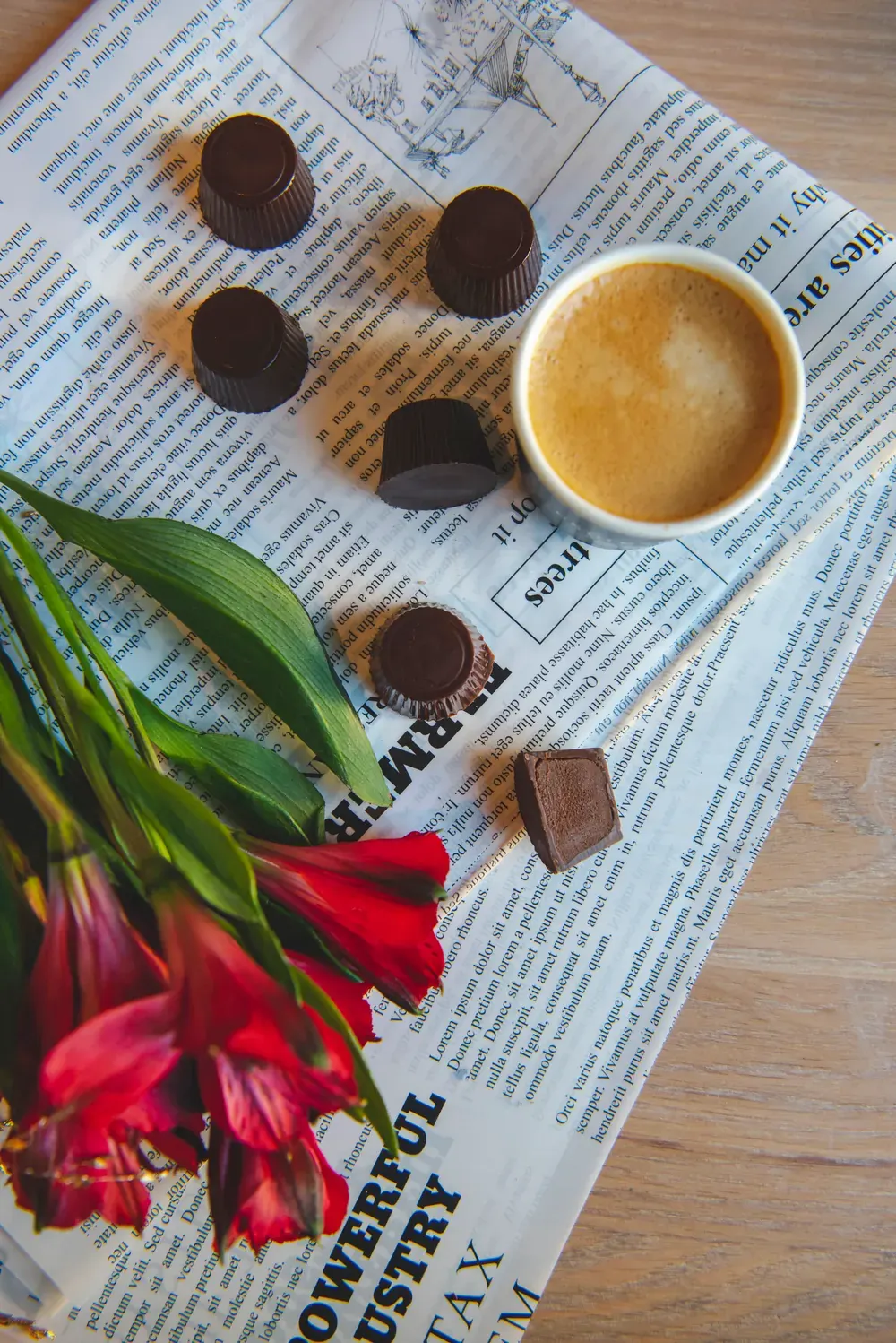 Bomboane de ciocolată neagră cu portocale Choco Toni, lângă un espresso și flori roșii