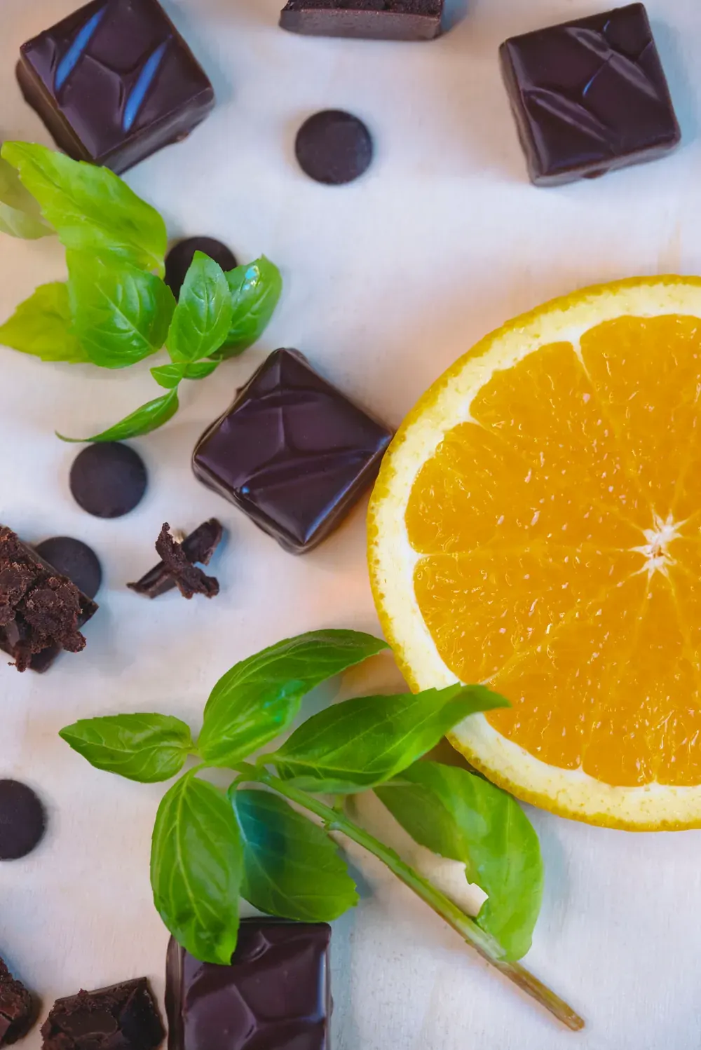 Bomboane de ciocolată neagră cu portocale și busuioc Choco Toni, văzute de sus, cu o felie de portocală