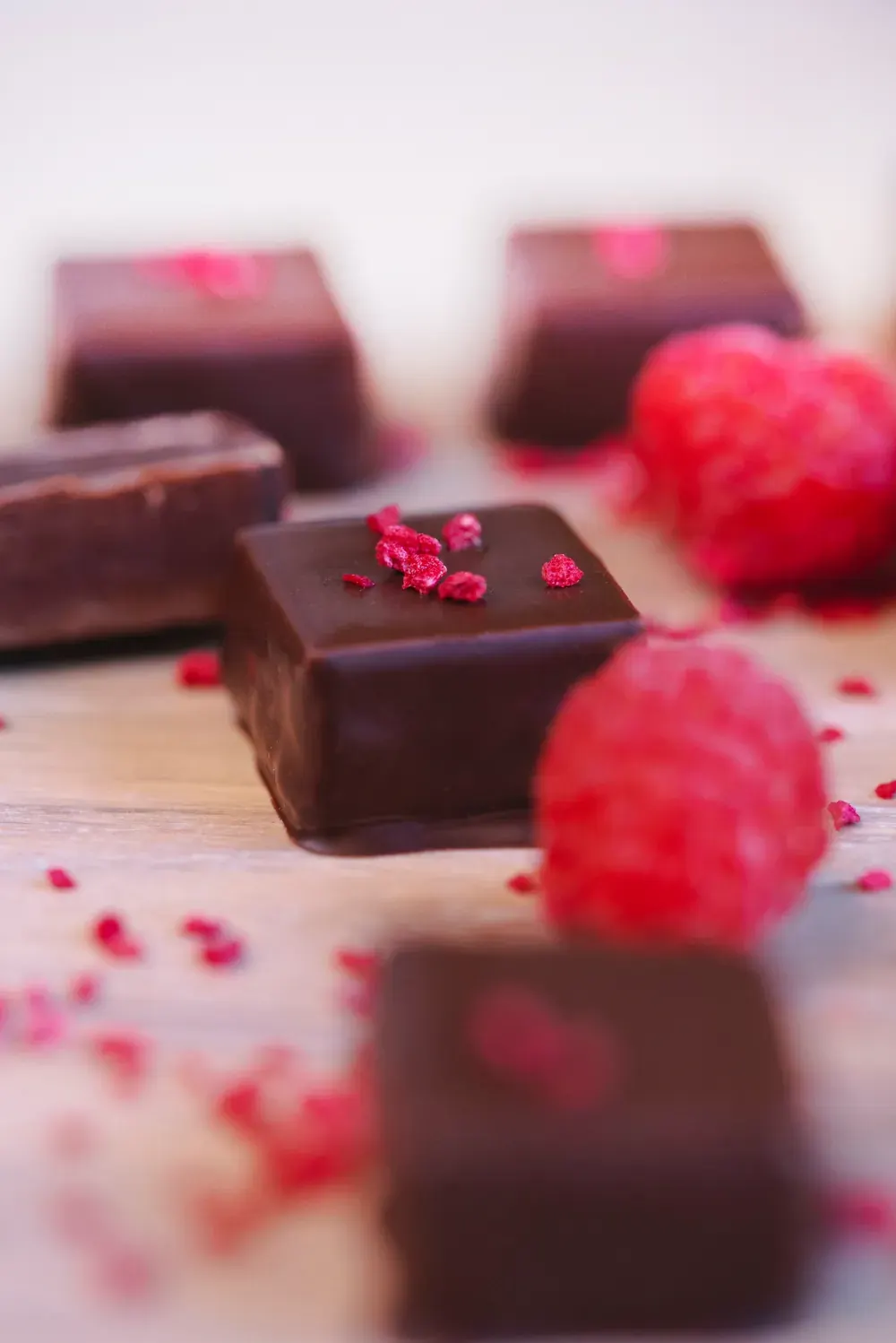 Bomboane de ciocolată neagră cu zmeură Choco Toni, decorate cu zmeură uscată, lângă zmeură proaspătă