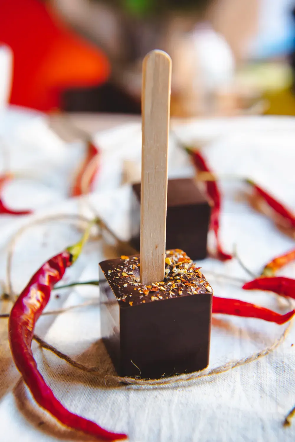 Ciocolată caldă neagră cu chilli Choco Toni pe băț, cu ardei iuți roșii în jur