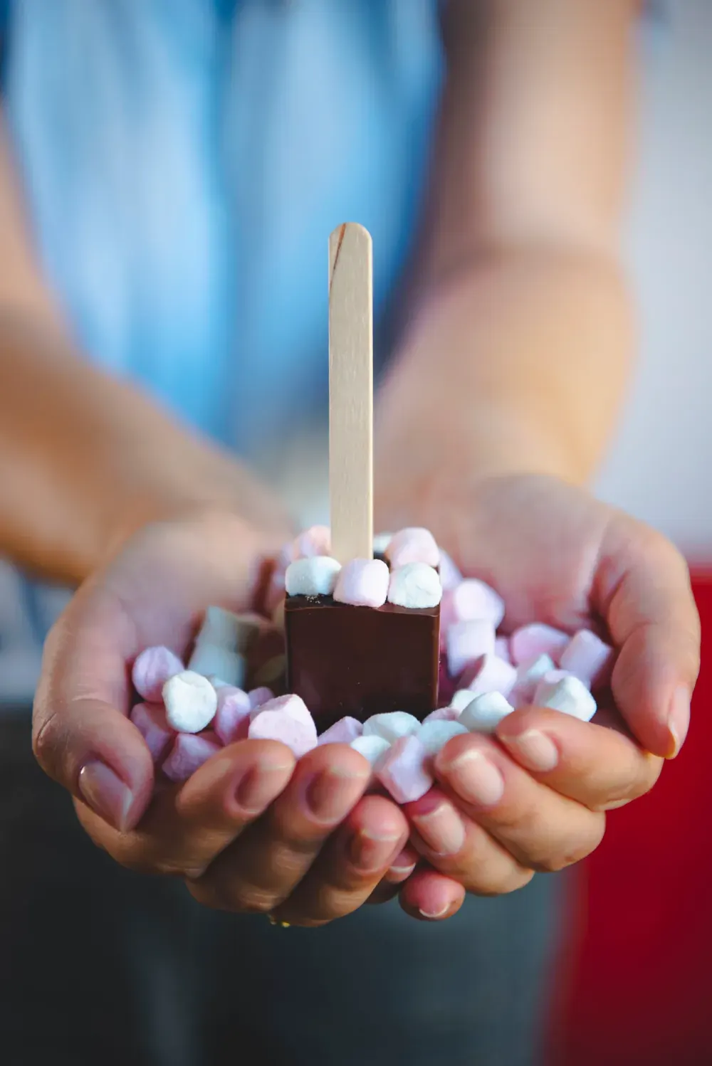 Ciocolată caldă neagră cu minibezele Choco Toni pe băț, ținută în palme