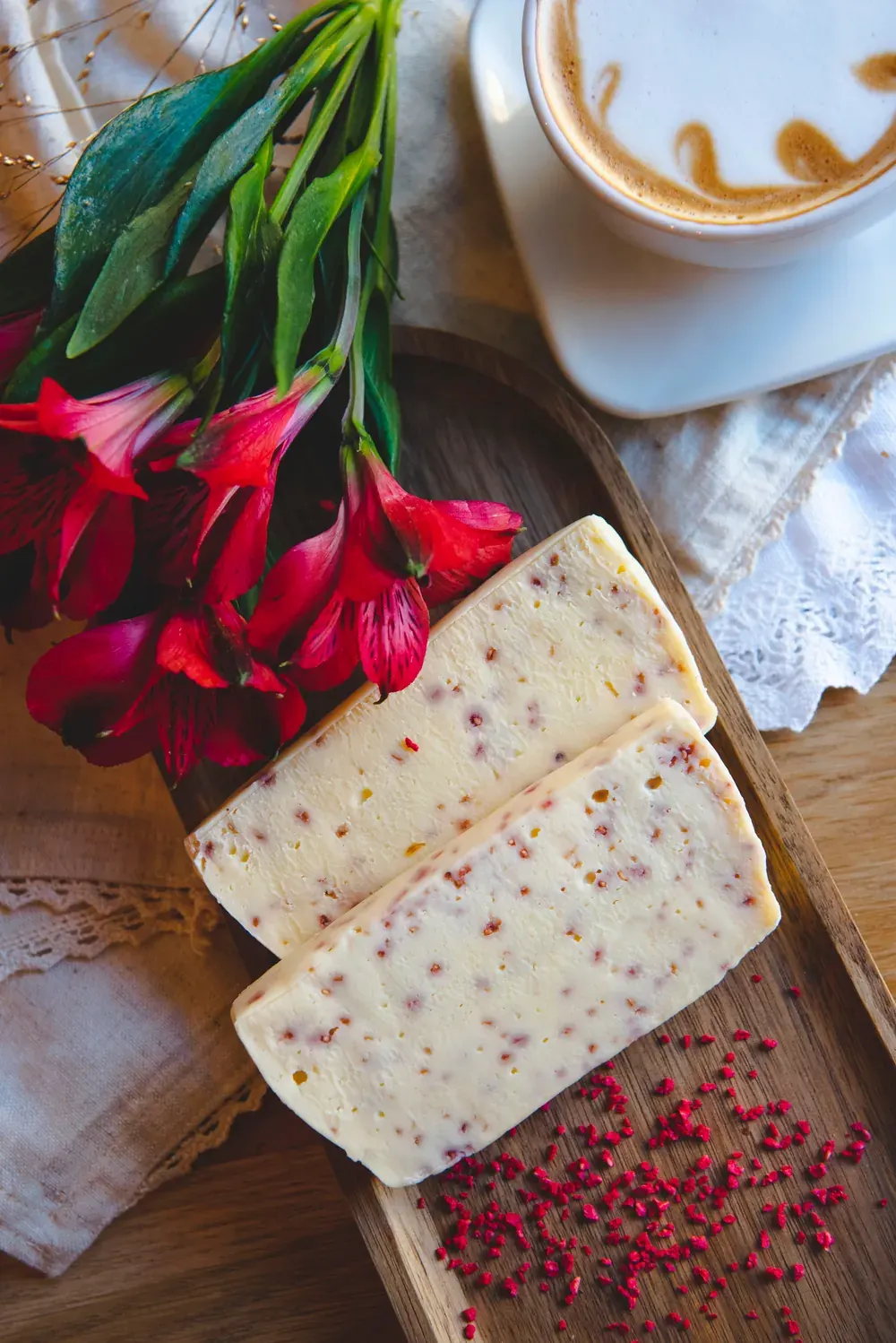 Felii de fudge de ciocolată albă cu zmeură și limoncello Choco Toni pe o tăviță de lemn, cu flori roșii
