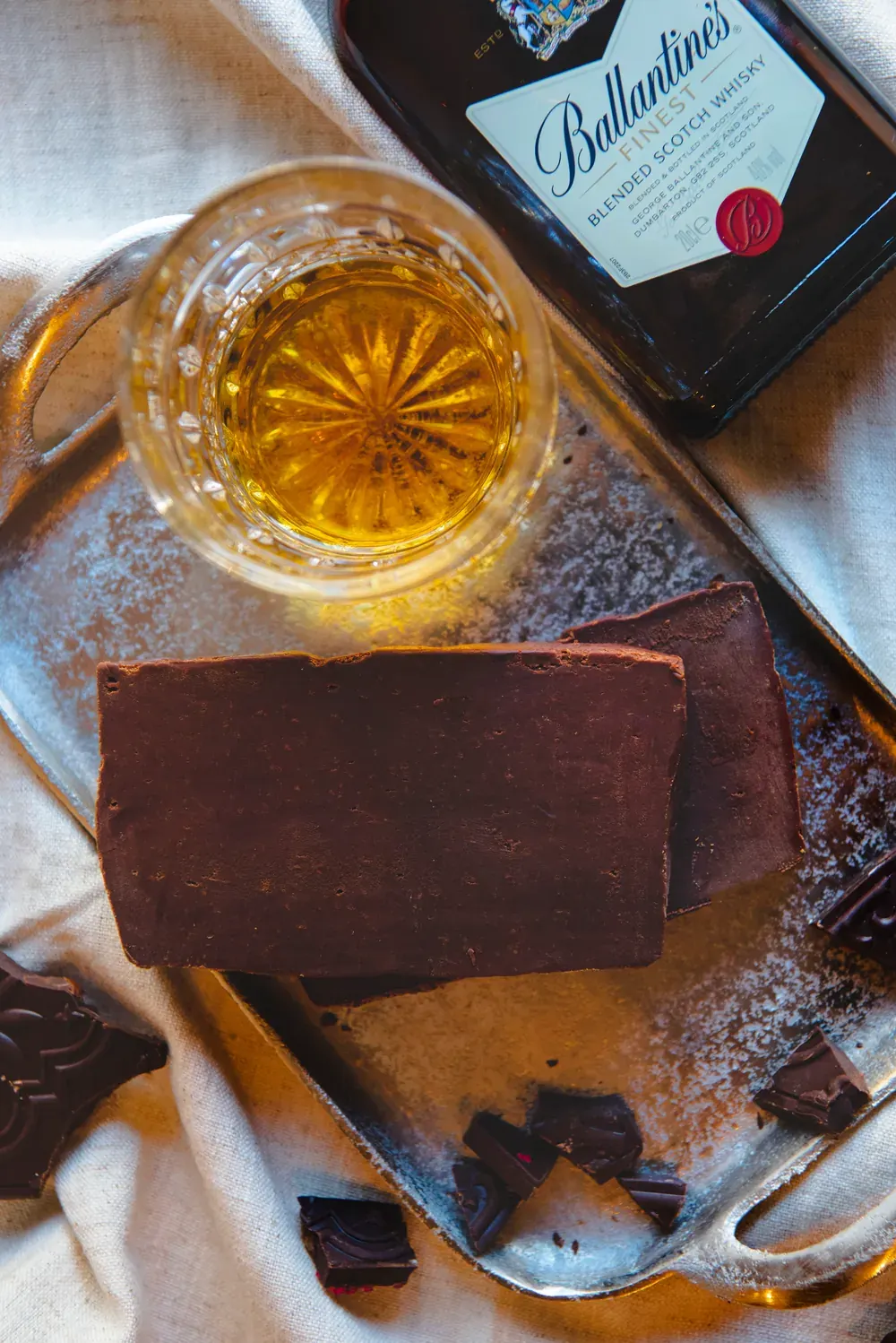 Felii de fudge de ciocolată cu cremă de whiskey Choco Toni, văzute de sus, lângă un pahar de whisky