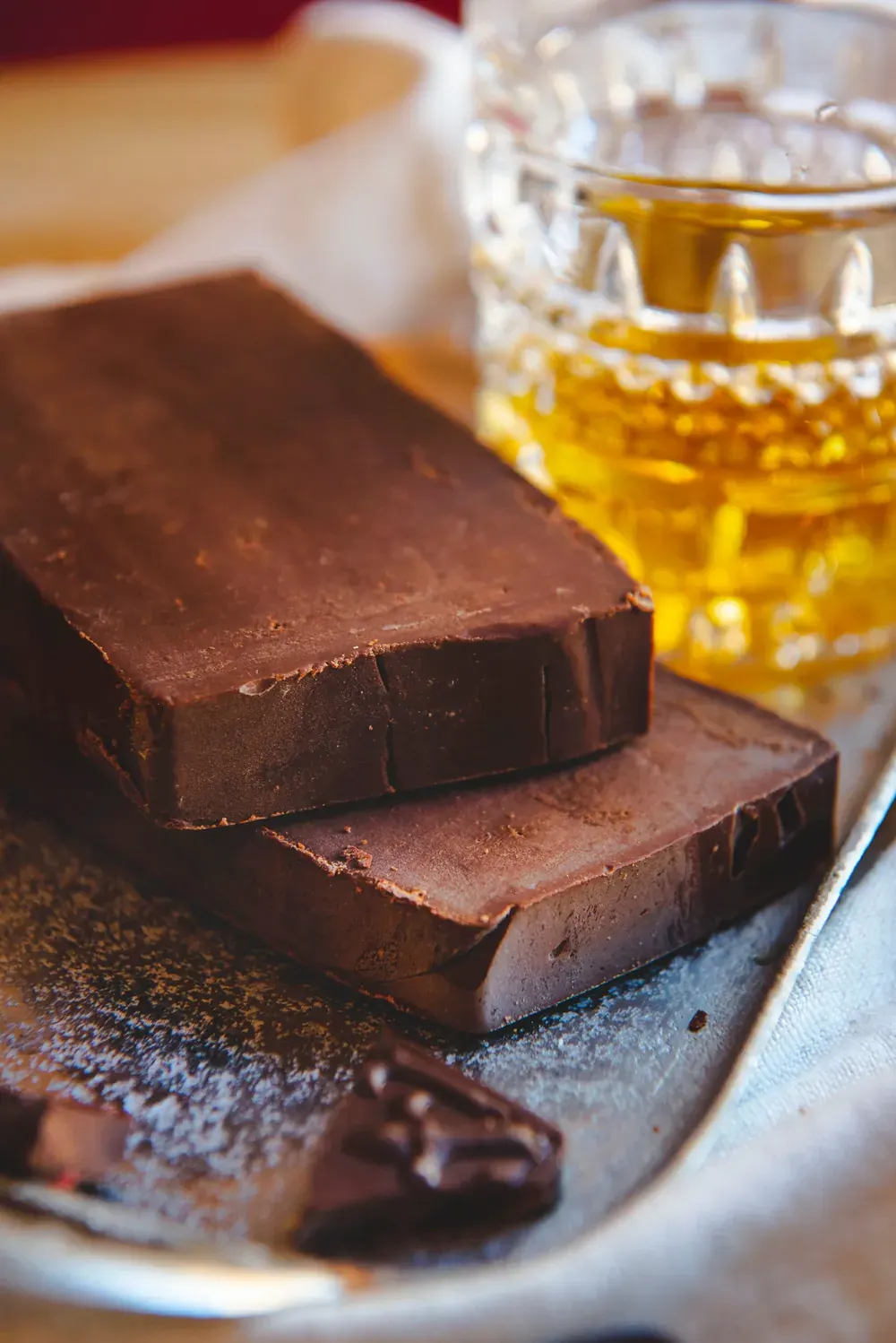 Fudge de ciocolată cu cremă de whiskey Choco Toni, de aproape, cu un pahar de whisky în spate