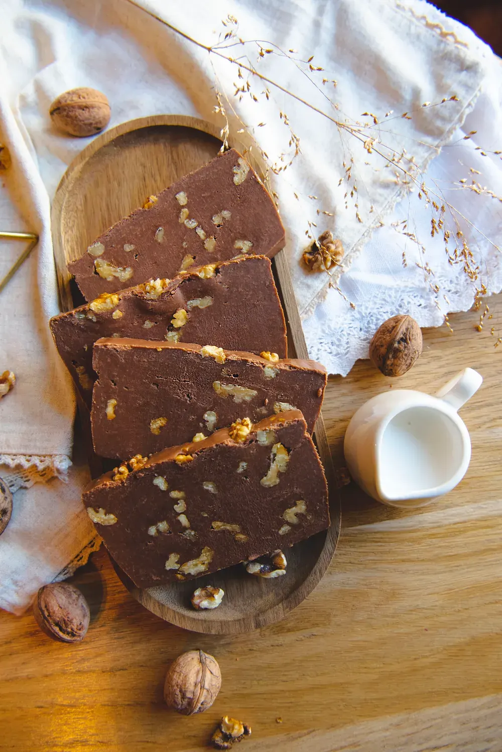 Felii de fudge de ciocolată cu lapte și nuci Choco Toni pe un platou de lemn, cu nuci întregi
