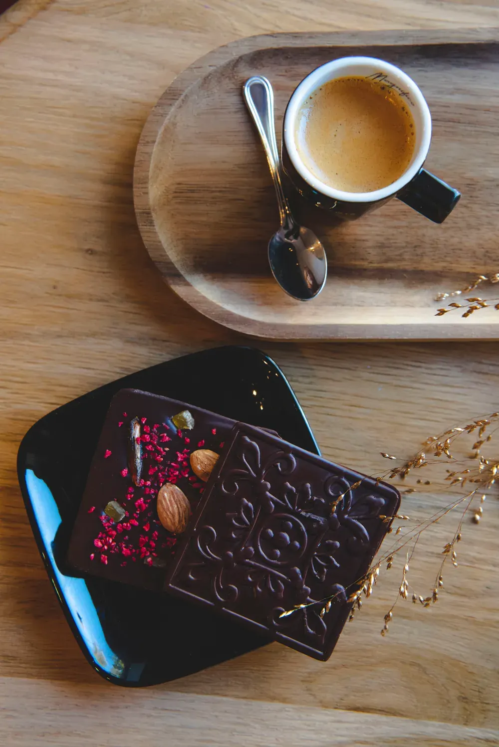 Tabletă de ciocolată neagră 54,5% Choco Toni cu fructe uscate, lângă un espresso