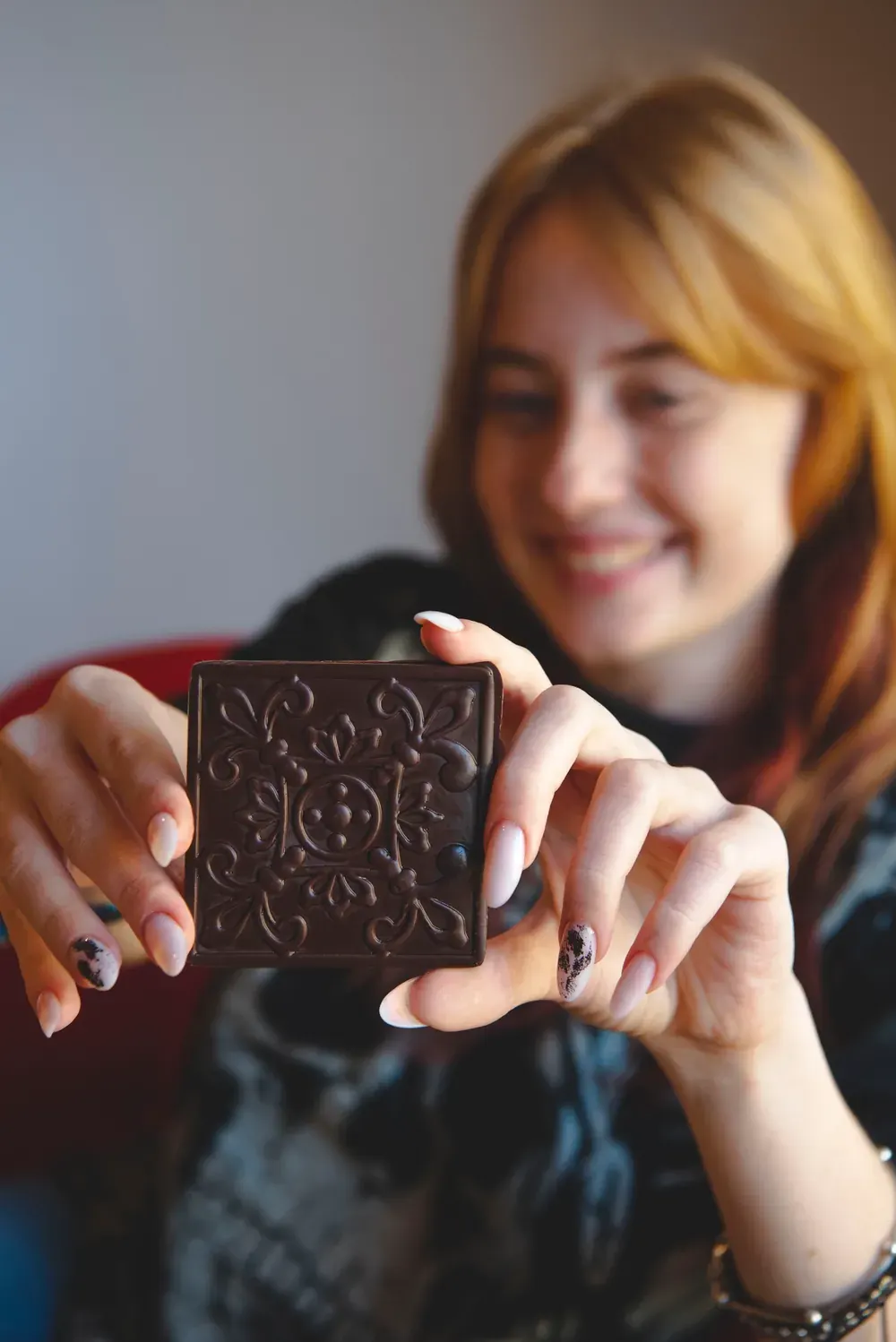 Tânără zâmbitoare care ține o tabletă de ciocolată neagră Choco Toni