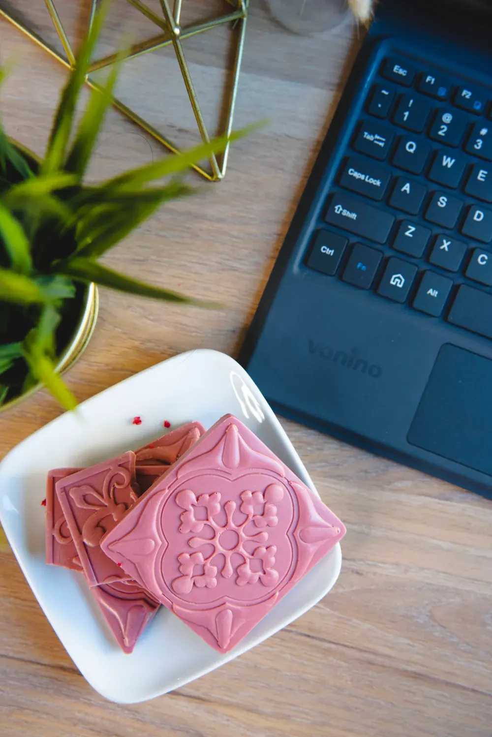 Tablete de ciocolată ruby Choco Toni pe o farfurioară albă, lângă o tastatură